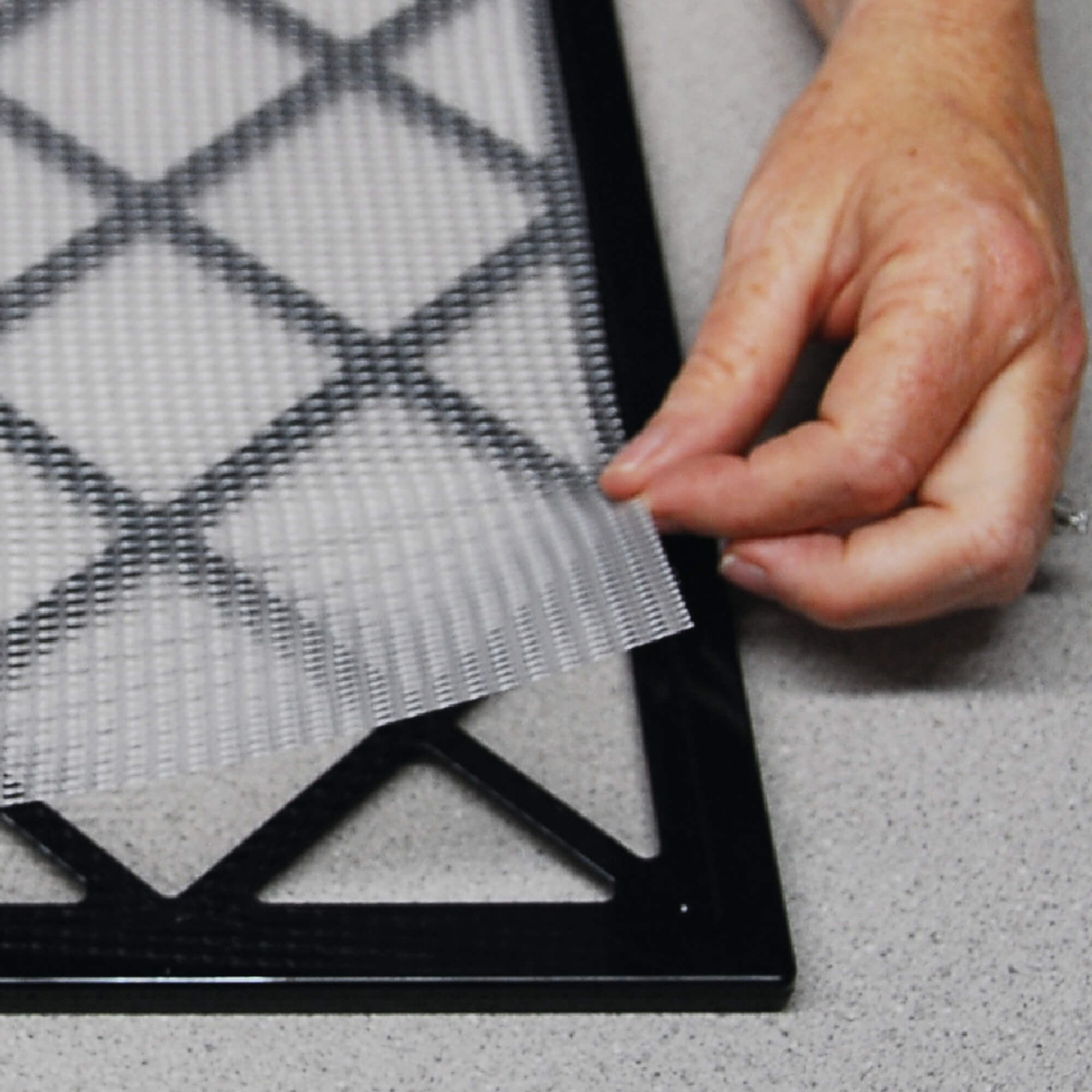 Excalibur dehydrator mesh sheet on a tray with the corner of the sheet being lifted.